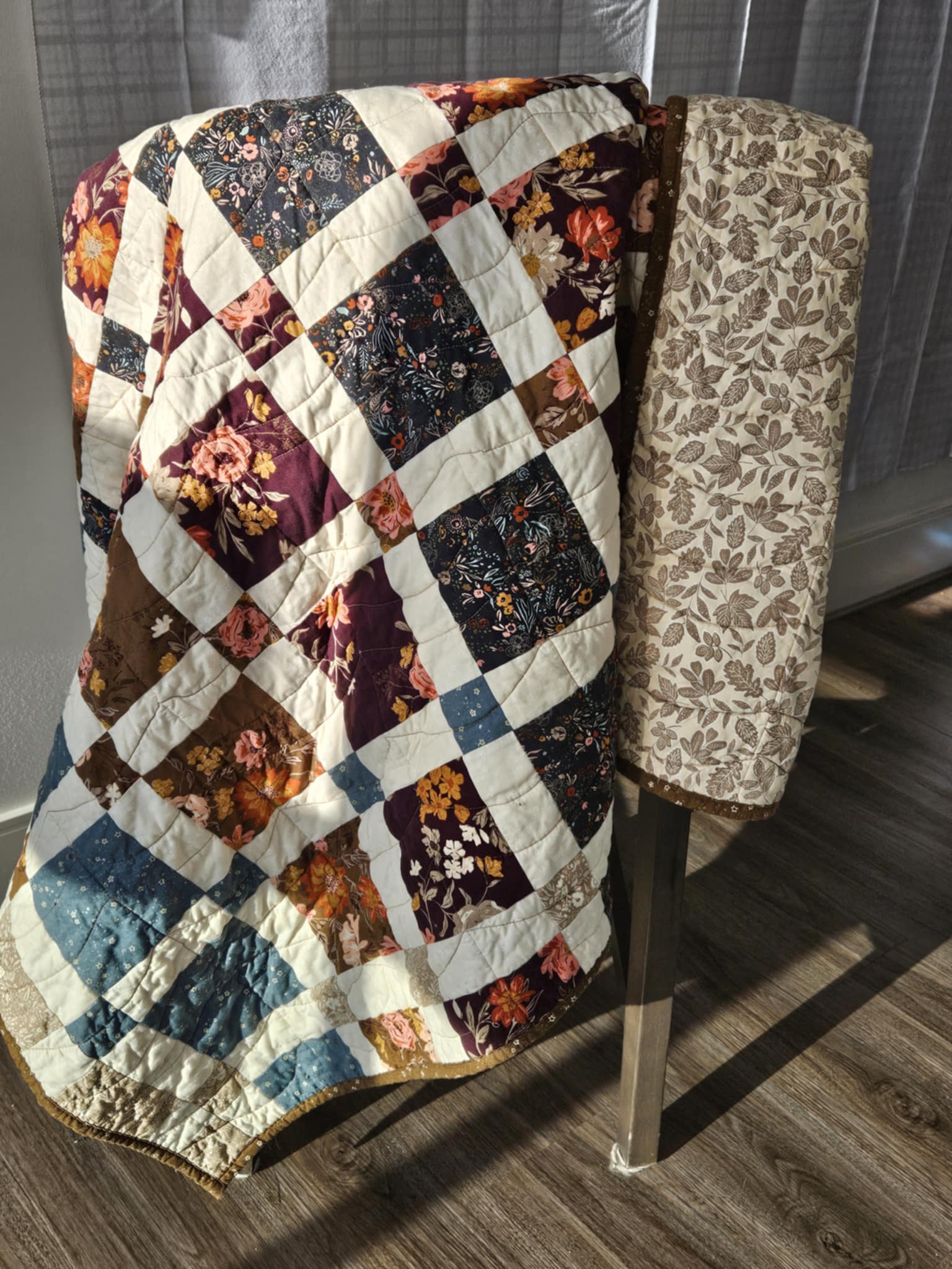 Floral quilt draped over a chair in the morning sunlight